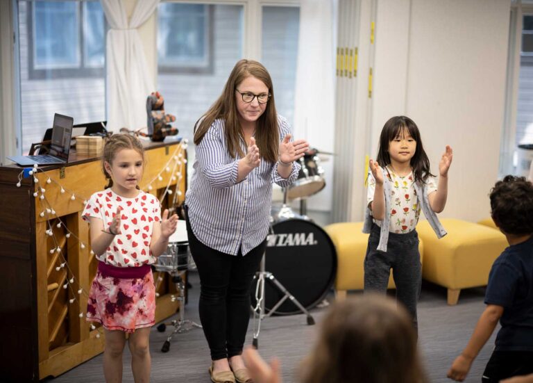 A music teacher claps with her students