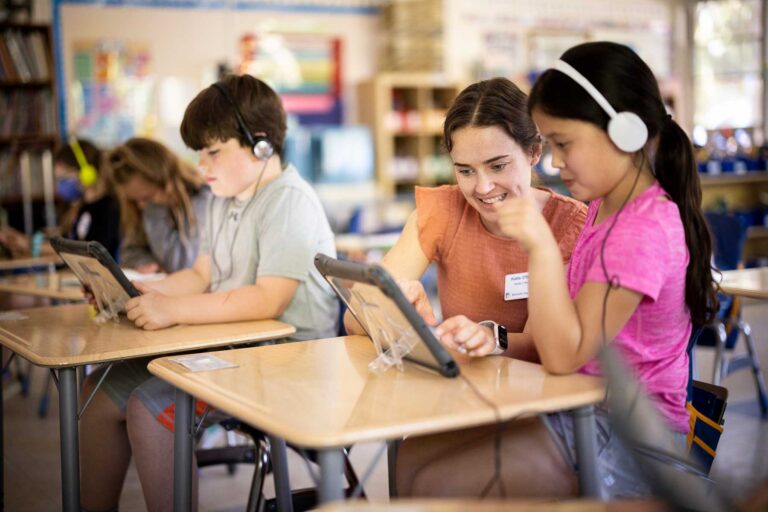 A teacher guides a student who is working on an iPad