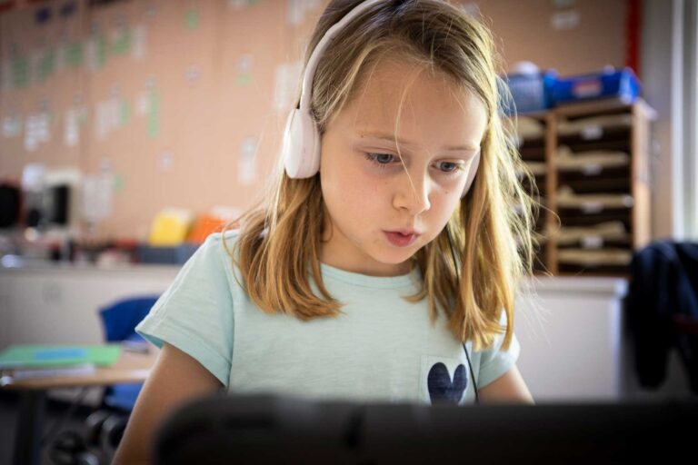 A student wearing headphones works on her iPad