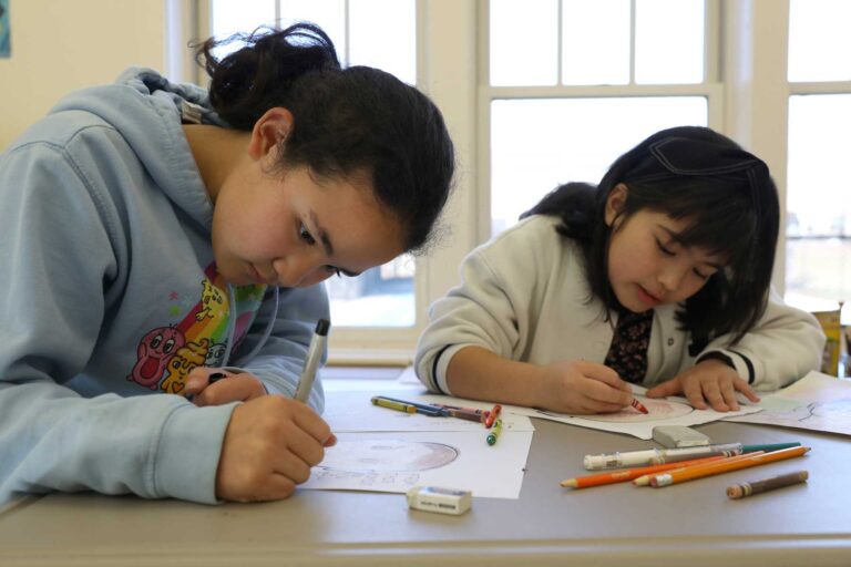 Two students focus on an activity at their desks