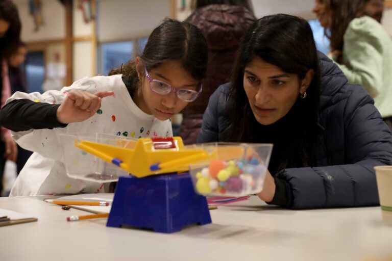 A first grader and parent use a scale to weigh their 100-day collection