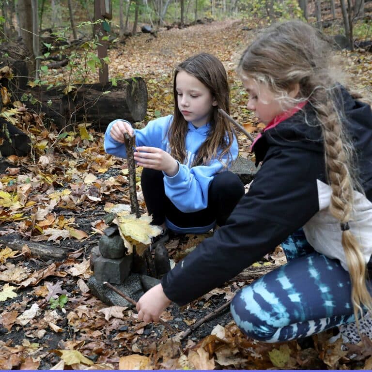 Two students build a cairn in the woods