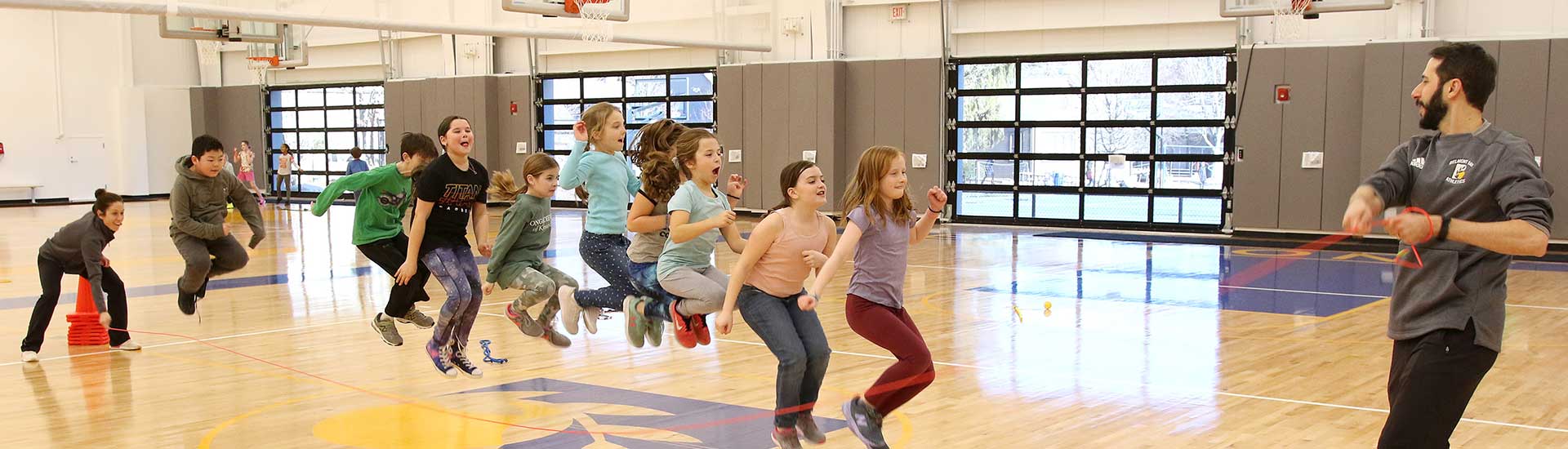 Several students jump rope together in the Barn gym