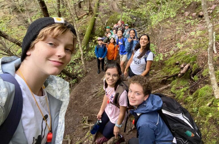 Seventh graders smile for a selfie while hiking at Mount Cardigan