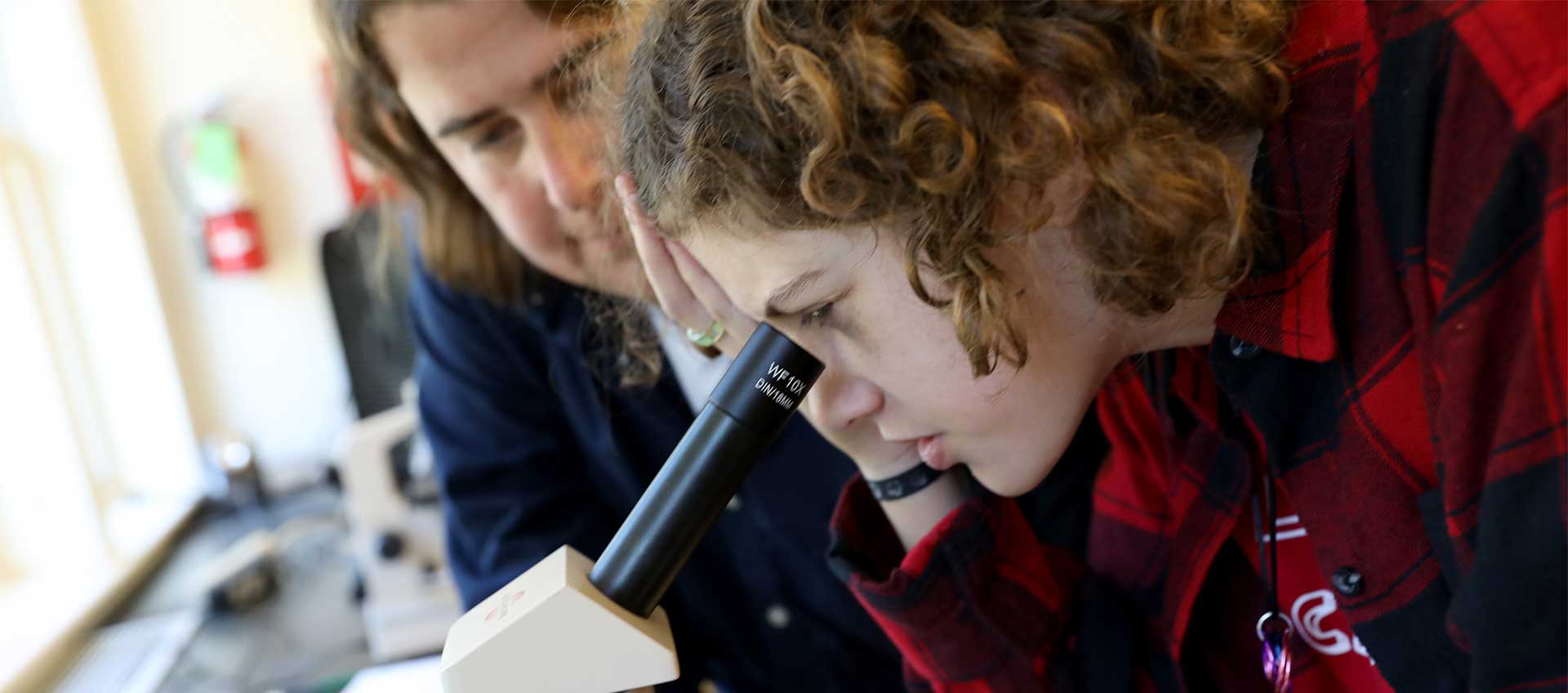 A student and teacher use a microscope in the science lab