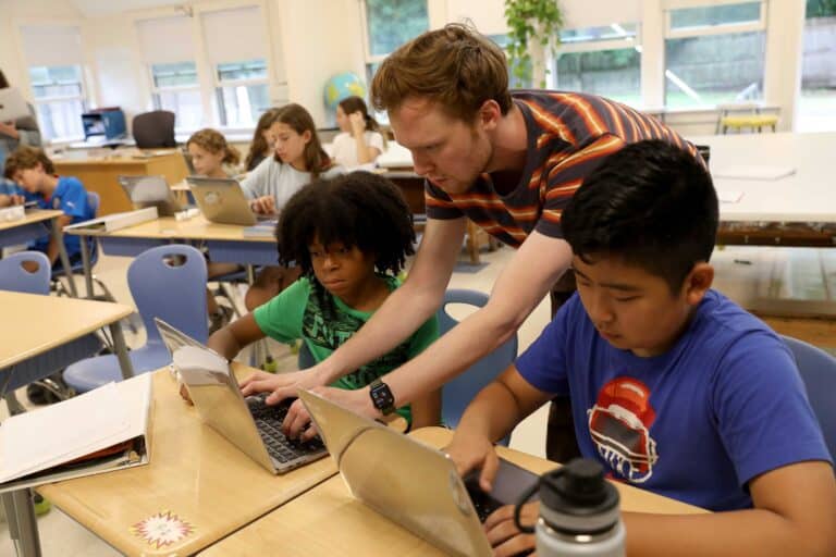 Two students work with a technology teacher