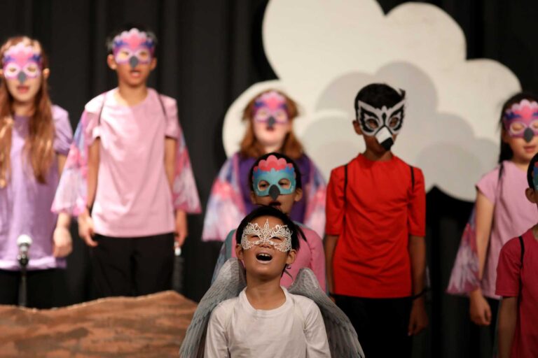 Third graders in masks and makeup on stage