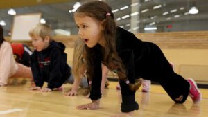 A pre-k student tries a plank in PE class