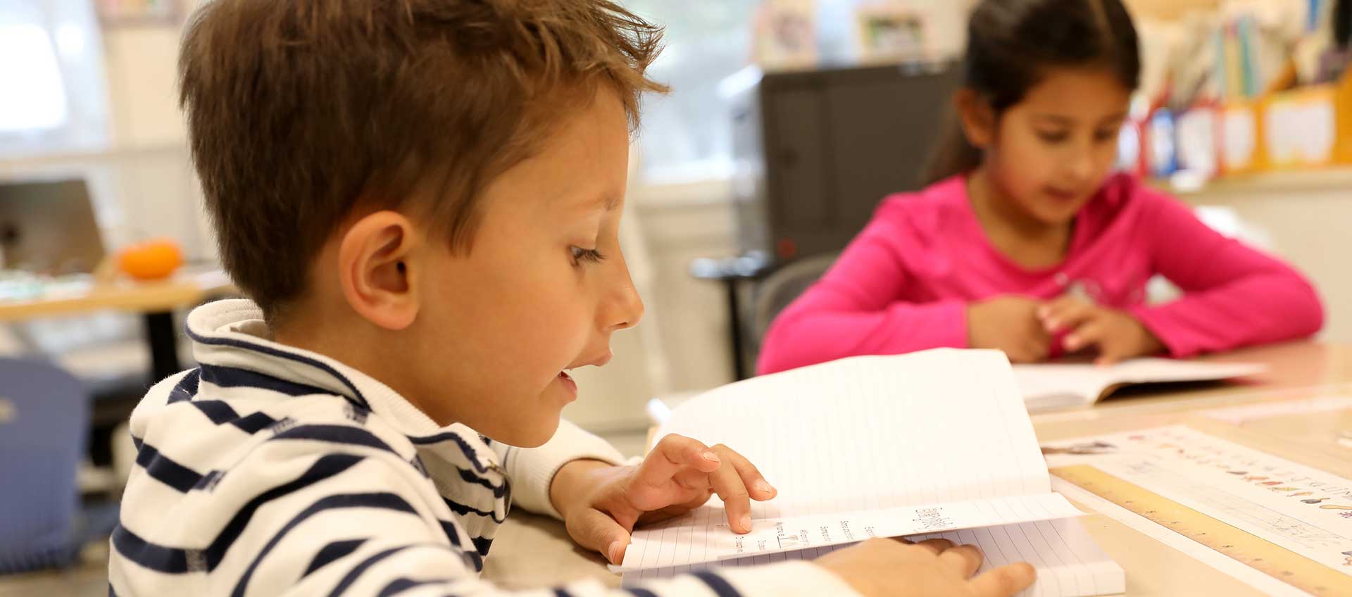 Two first grade students at their desks reading poetry