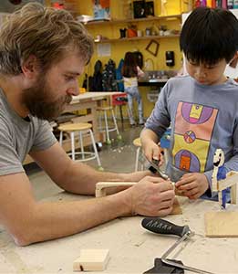 A teacher assists a student in the woodworking studio