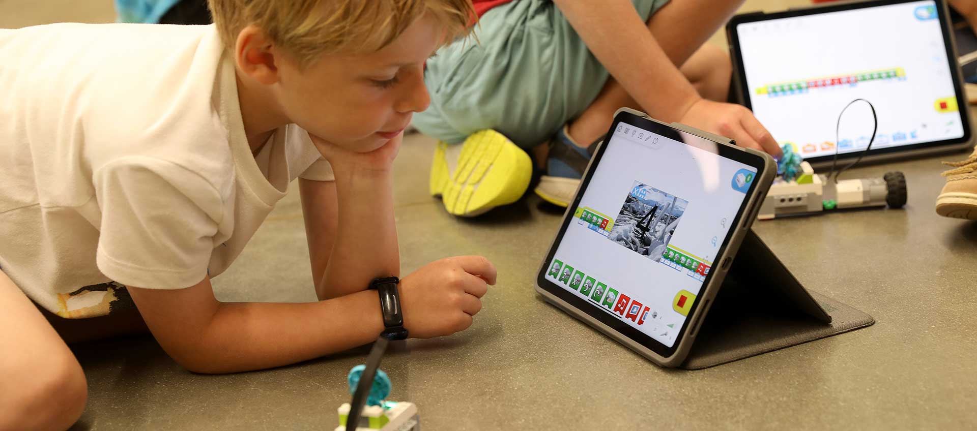 A camper looks at his iPad while programming a robot