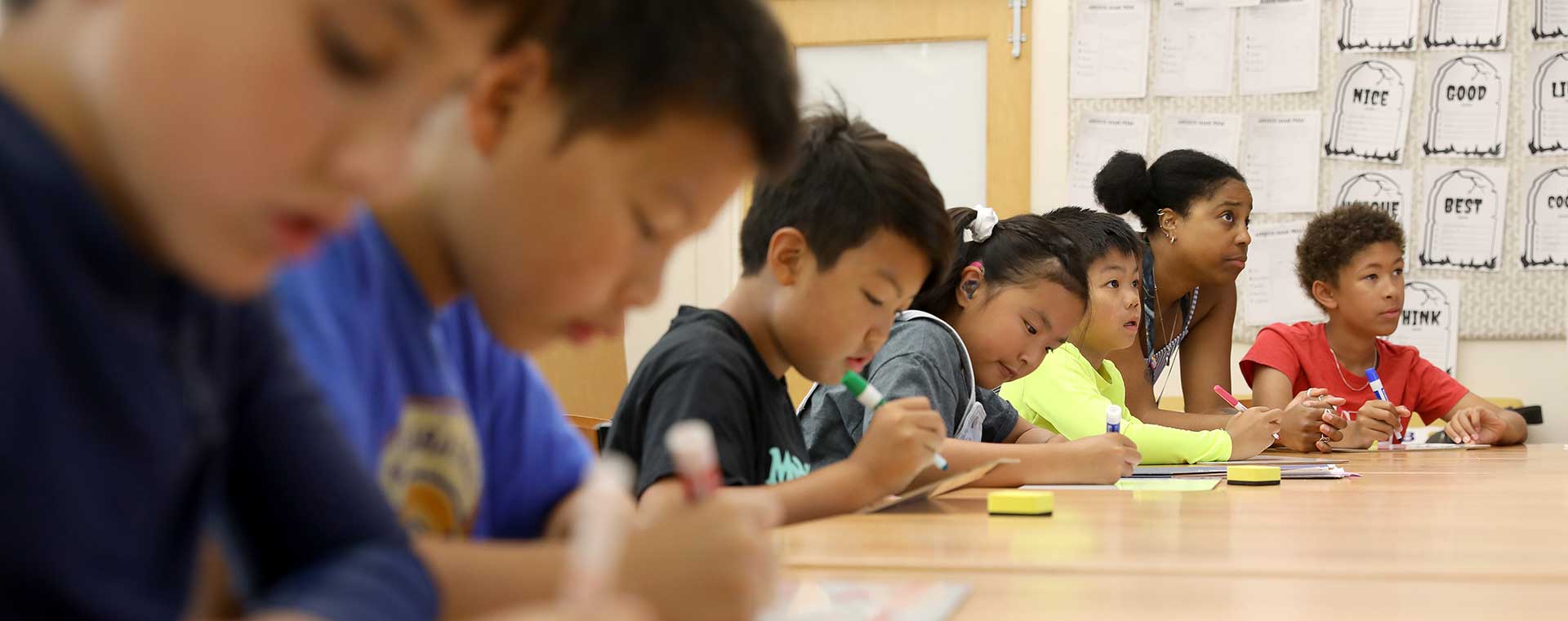 A teacher and five students work on a writing assignment together